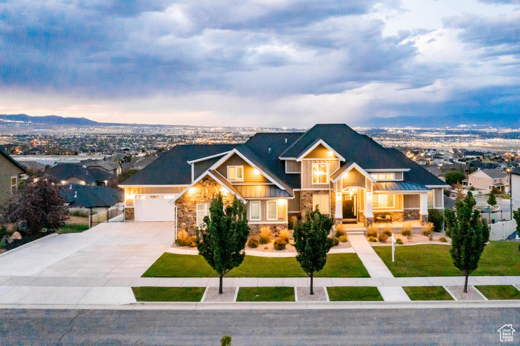 Craftsman house featuring stone siding, concrete driveway, a standing seam roof, and an attached garage