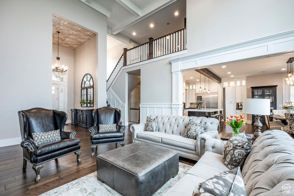 Living room with a chandelier, a high ceiling, wood-type flooring, stairs, and recessed lighting
