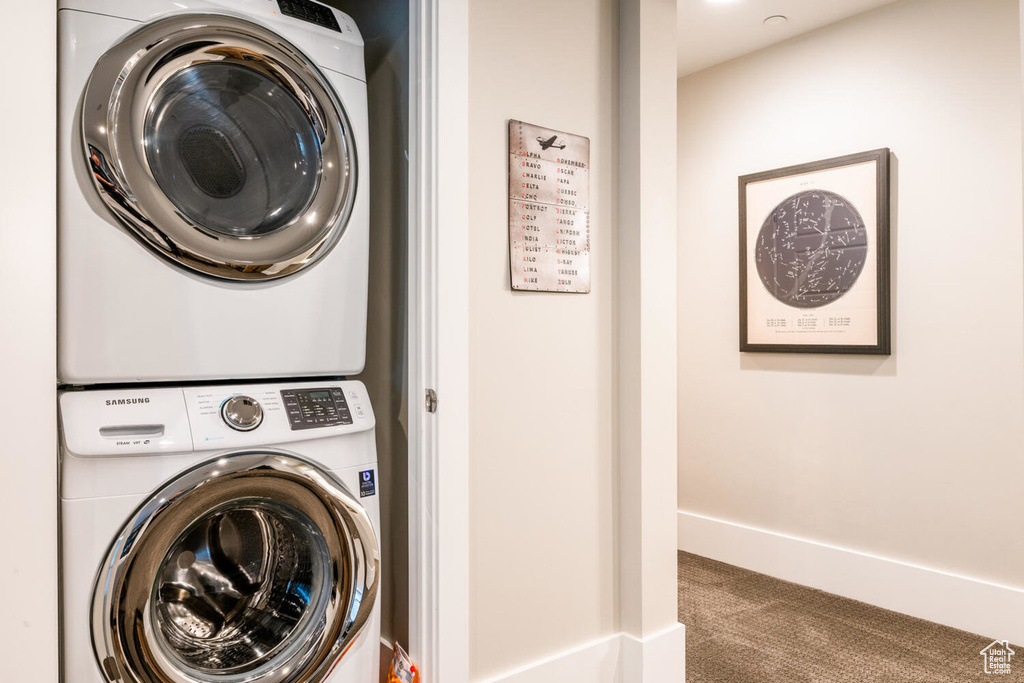 Washroom with stacked washer / dryer, carpet, and baseboards
