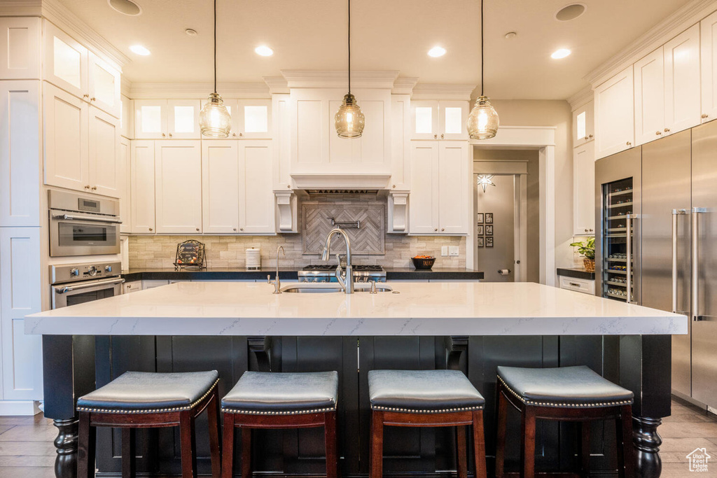 Kitchen with built in refrigerator, a sink, decorative backsplash, white cabinetry, and recessed lighting