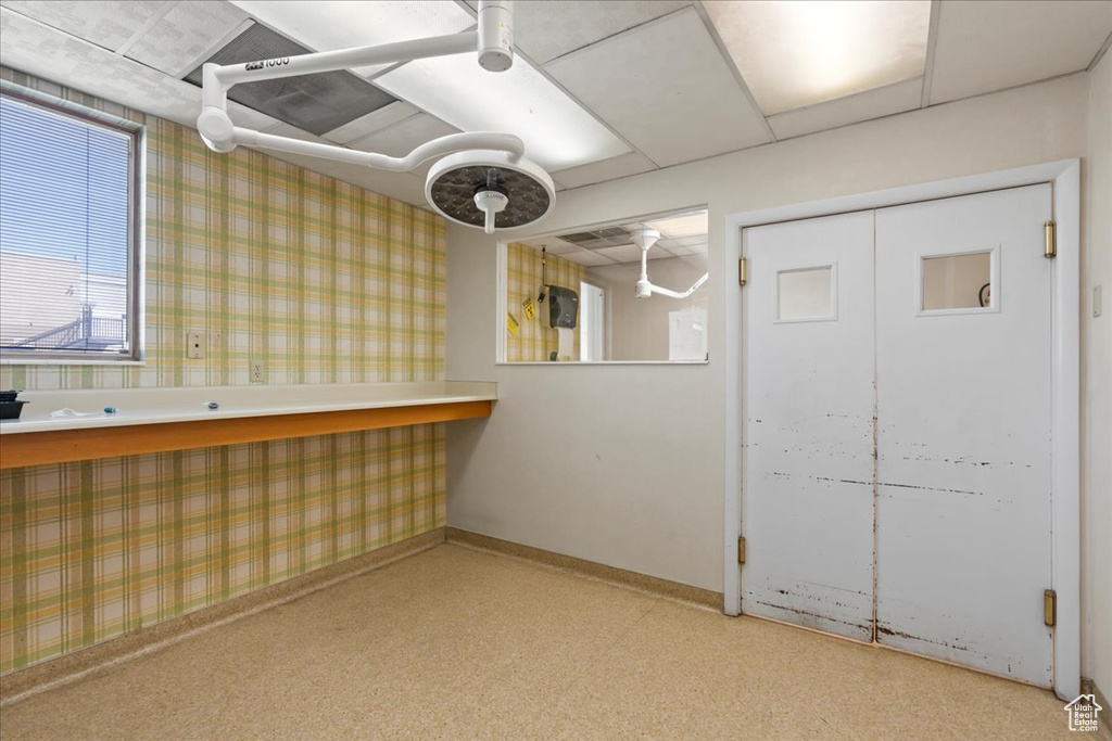 Below grade area featuring wallpapered walls, baseboards, and light colored carpet