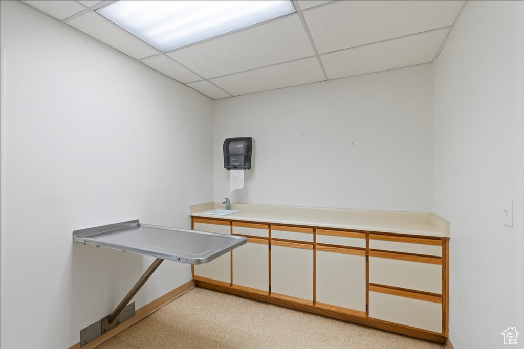 Unfurnished office featuring a drop ceiling, baseboards, and a sink