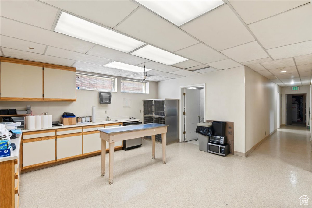 Kitchen with light countertops, baseboards, a drop ceiling, and a sink