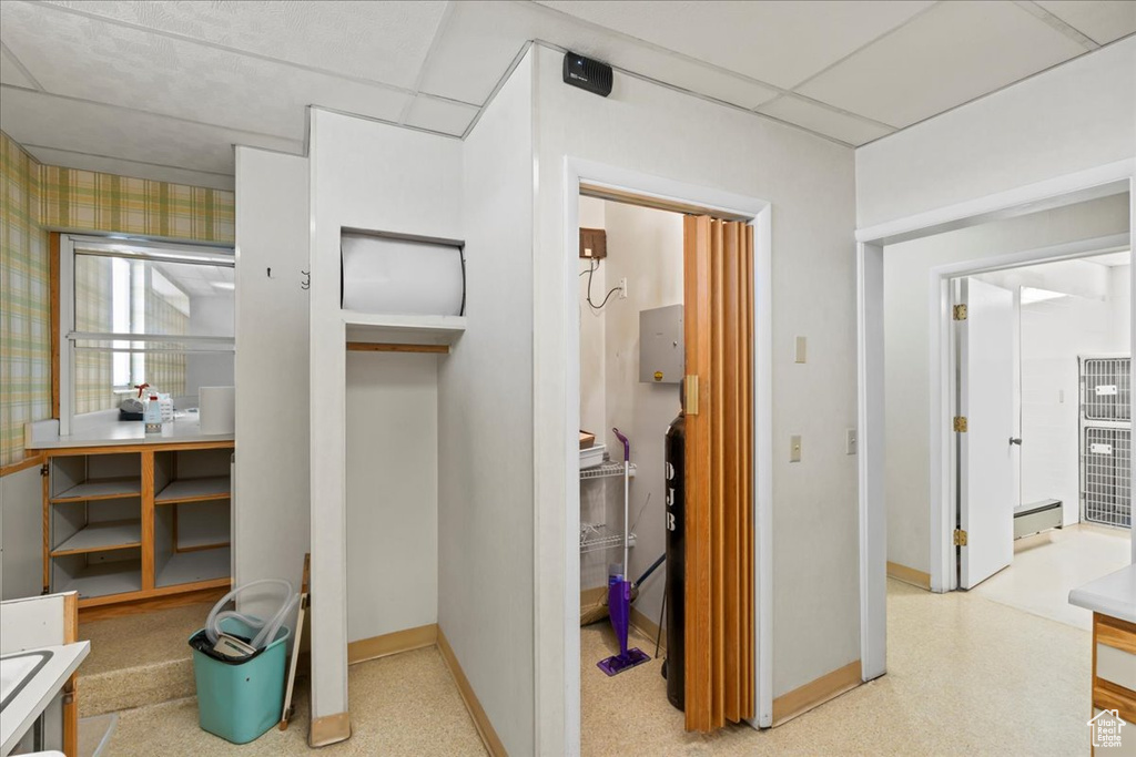 Corridor with baseboards, a baseboard heating unit, and a drop ceiling