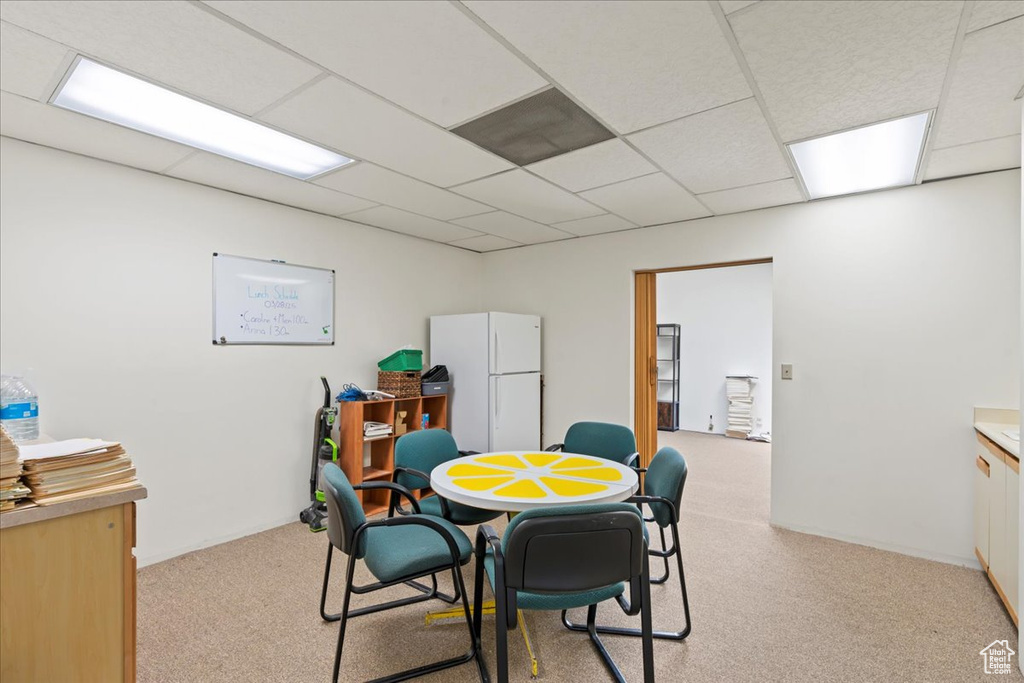 Dining space with light carpet and a paneled ceiling