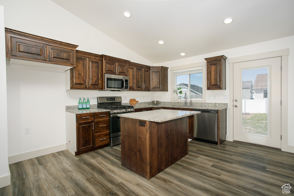 Kitchen featuring stainless steel appliances, vaulted ceiling, dark wood-style floors, a kitchen island, and a sink