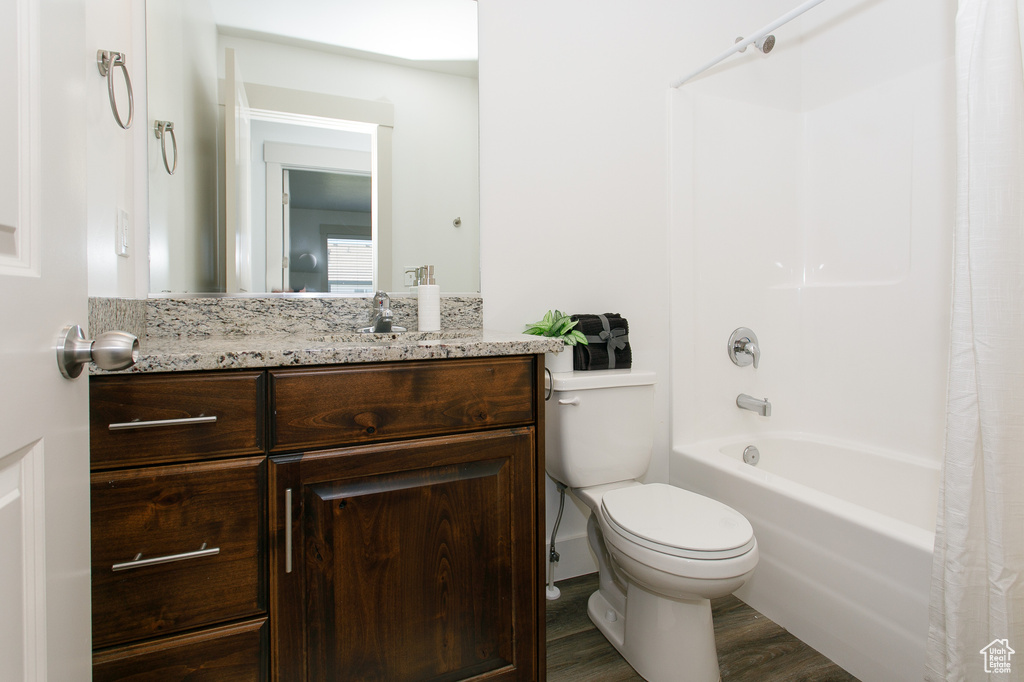 Bathroom with toilet, wood finished floors, vanity, and shower / bath combo