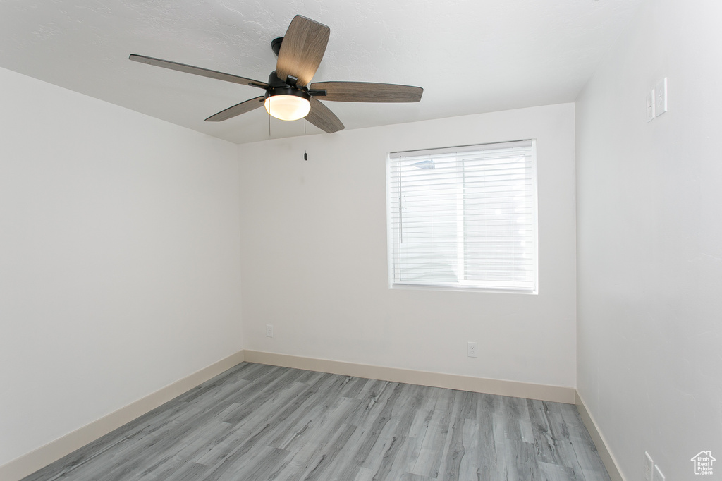 Spare room featuring a ceiling fan, light wood finished floors, and baseboards