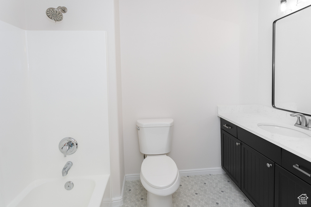 Bathroom featuring toilet, vanity, baseboards, bathing tub / shower combination, and tile patterned flooring