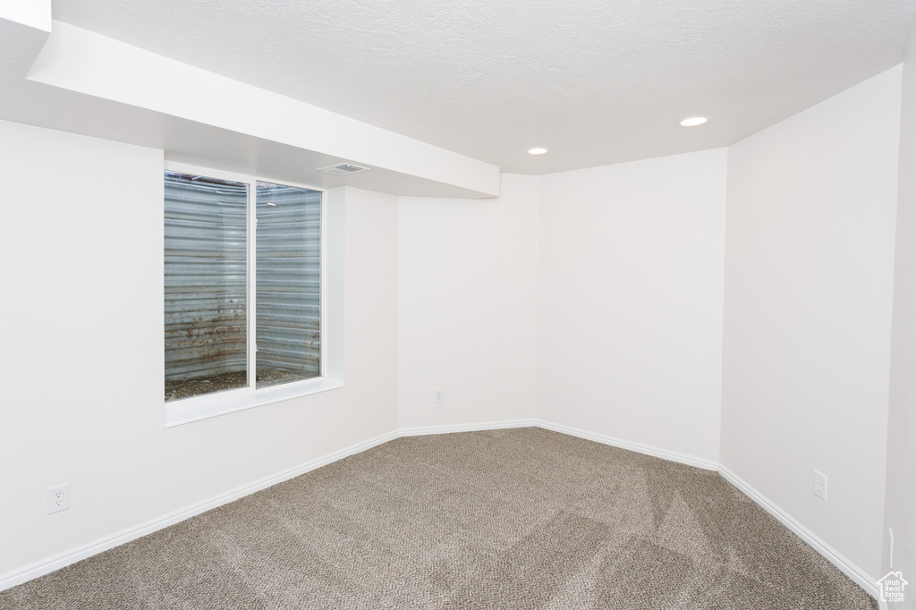 Empty room featuring carpet flooring, recessed lighting, and baseboards