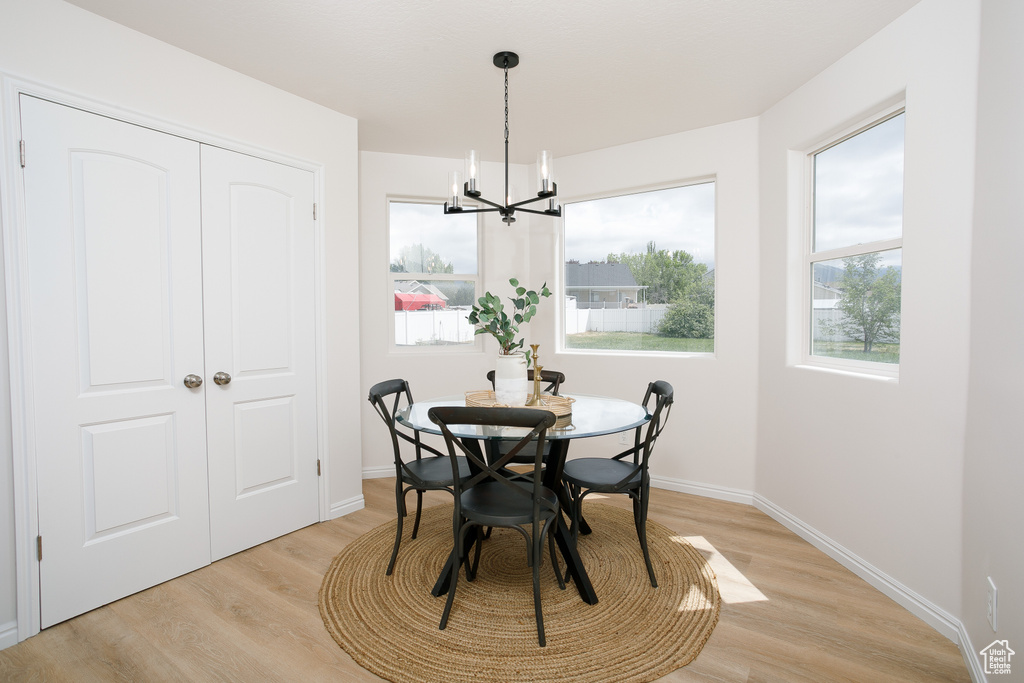 Dining area featuring light wood-style flooring, a chandelier, and baseboards