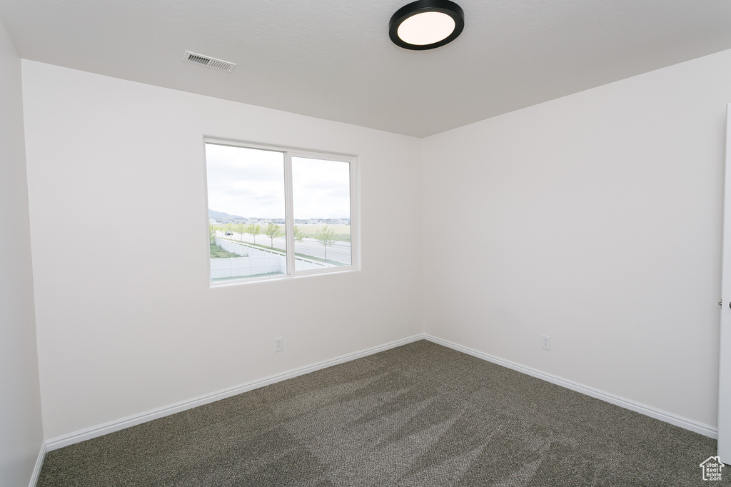 Spare room with dark colored carpet and baseboards