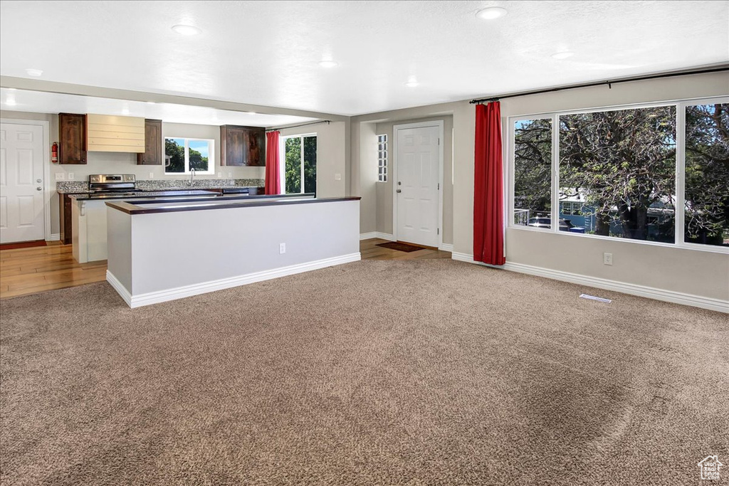 Kitchen featuring light carpet, dark countertops, plenty of natural light, baseboards, and recessed lighting