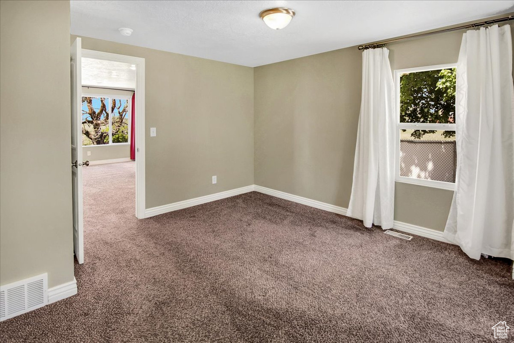 Empty room featuring carpet flooring, baseboards, and a smoke detector