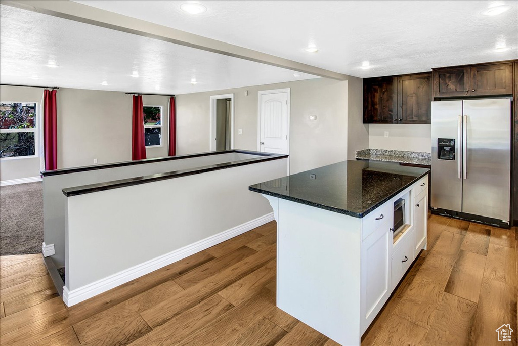 Kitchen with appliances with stainless steel finishes, a center island, baseboards, light wood-style floors, and recessed lighting