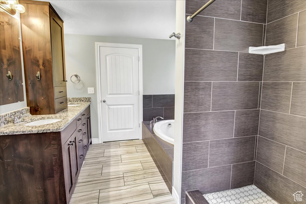 Bathroom with a tile shower, double vanity, and a garden tub