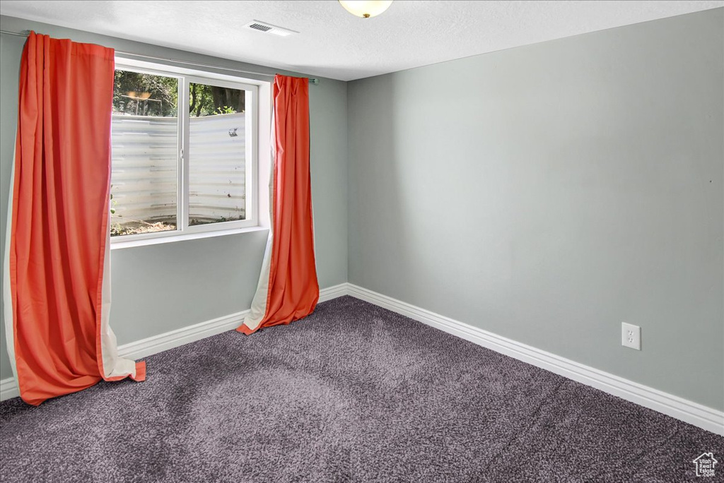 Carpeted spare room featuring baseboards and a textured ceiling