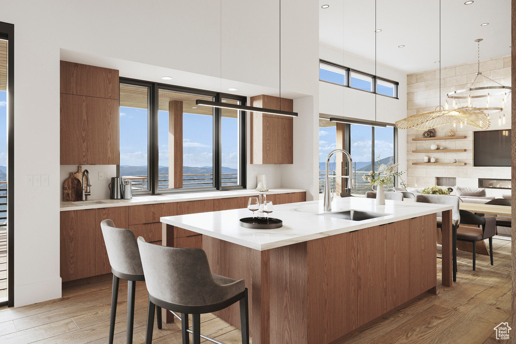Kitchen with a sink, modern cabinets, light wood-type flooring, light countertops, and brown cabinetry