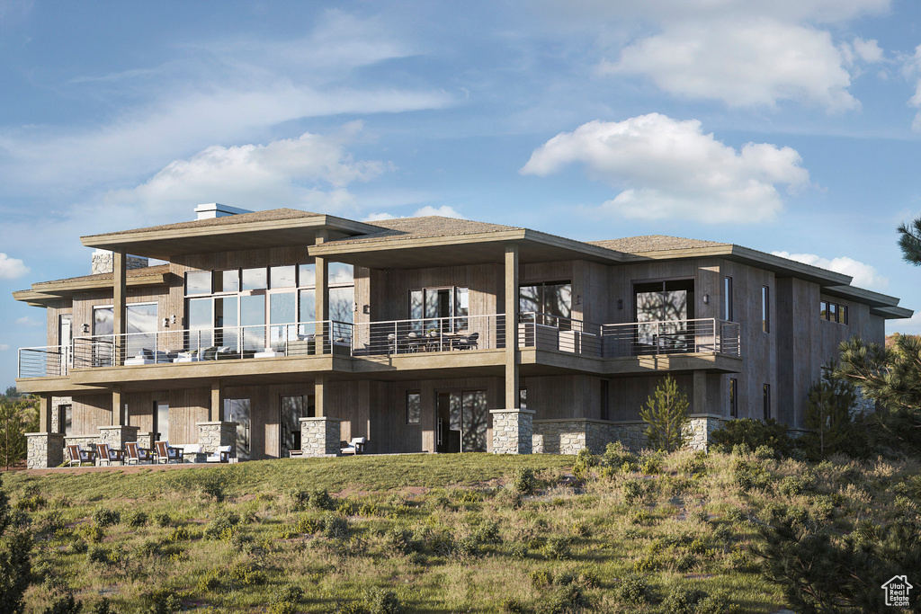 Rear view of house with stone siding and a balcony