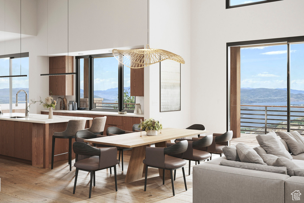 Dining room with a high ceiling, light wood-style floors, and a water and mountain view