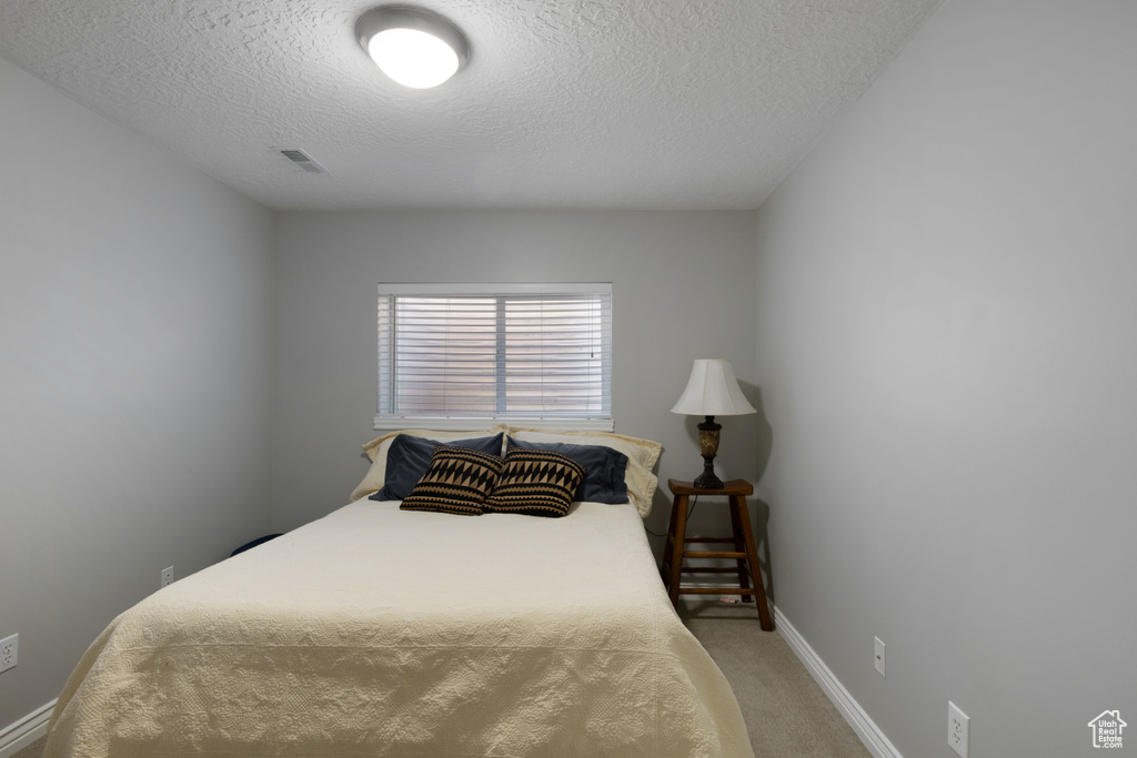 Carpeted bedroom with a textured ceiling and baseboards