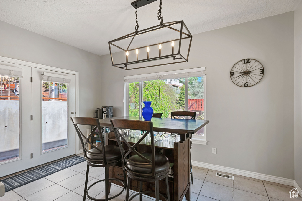 Dining area featuring light tile patterned floors, baseboards, a textured ceiling, and french doors