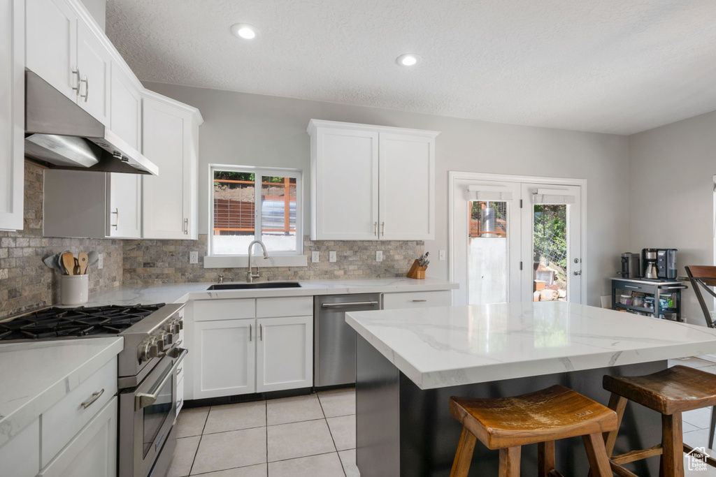 Kitchen featuring a sink, appliances with stainless steel finishes, under cabinet range hood, tasteful backsplash, and recessed lighting