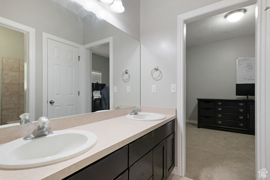 Bathroom featuring double vanity and a textured ceiling