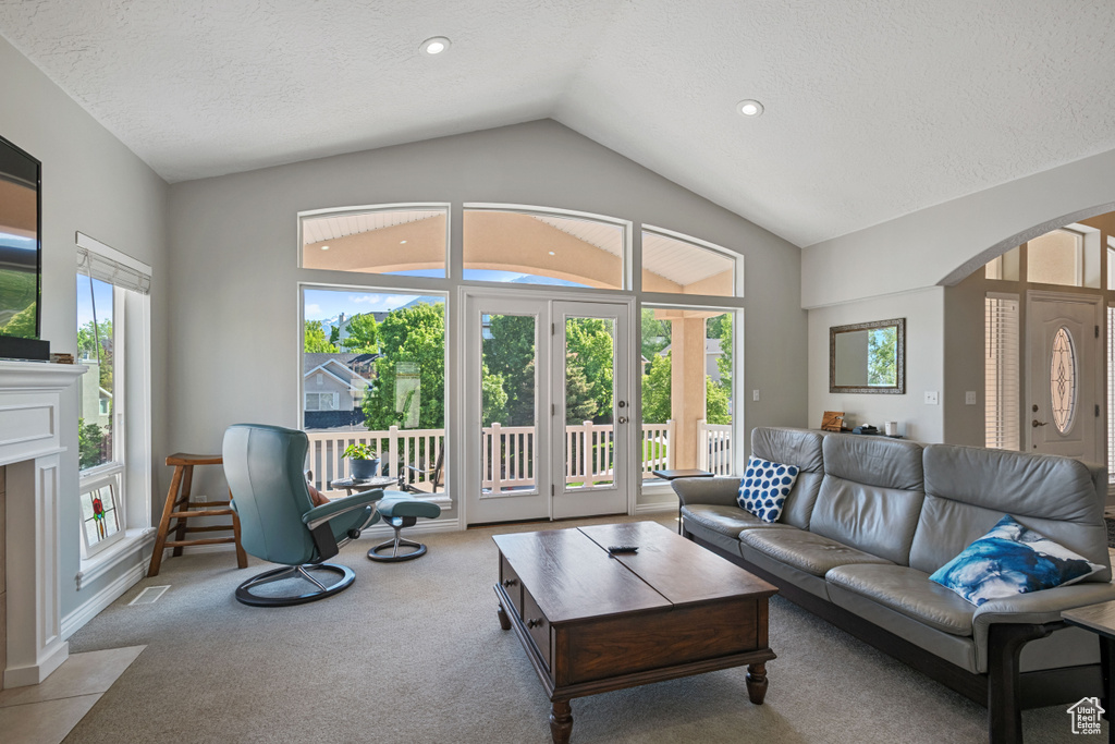 Living area with arched walkways, lofted ceiling, carpet flooring, a textured ceiling, and recessed lighting