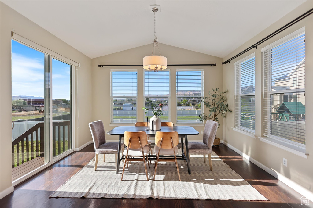 Dining room featuring lofted ceiling, a chandelier, dark wood-style floors, and baseboards