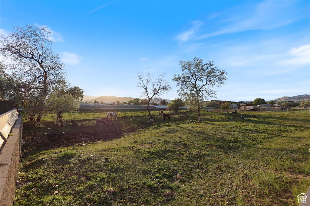 View of yard with fence, a rural view, and a mountain view