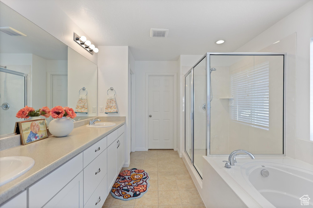 Bathroom with a shower stall, a garden tub, double vanity, recessed lighting, and tile patterned flooring