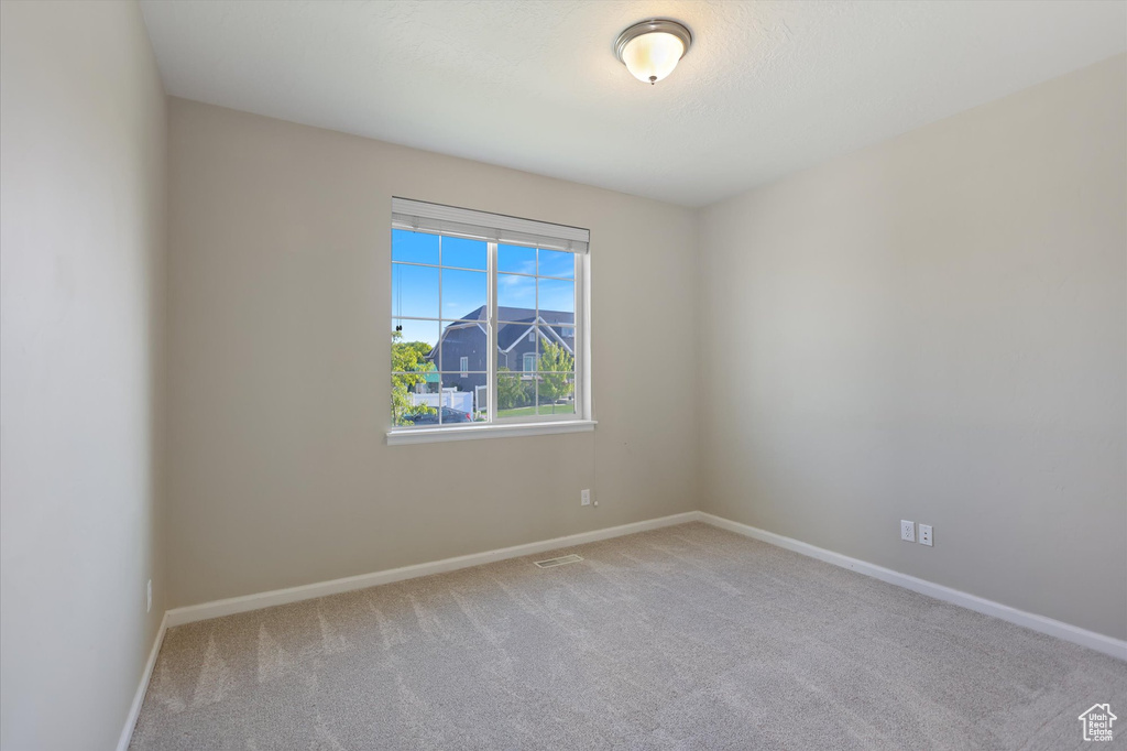 Carpeted spare room featuring baseboards