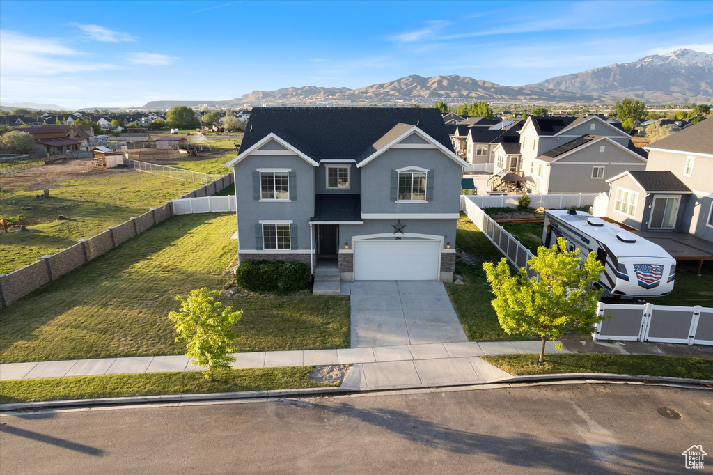 Traditional home featuring concrete driveway, stucco siding, a mountain view, a garage, and stone siding