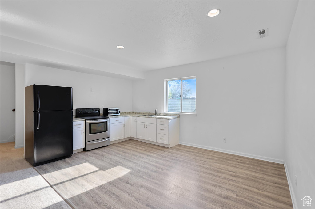 Kitchen featuring stainless steel appliances, white cabinetry, light wood-style flooring, baseboards, and recessed lighting