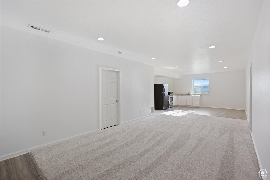 Unfurnished living room with recessed lighting, baseboards, and light carpet