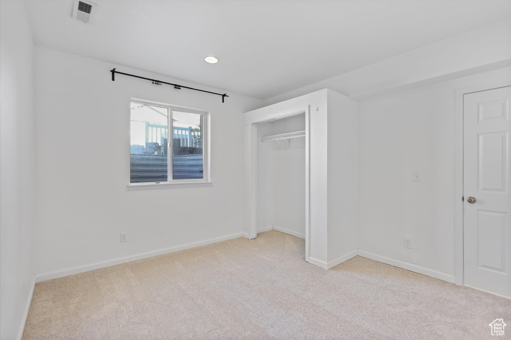 Unfurnished bedroom with light colored carpet, baseboards, a closet, and recessed lighting