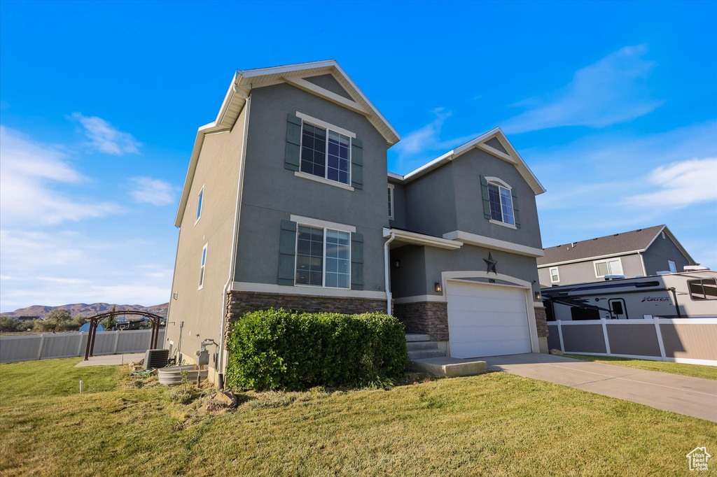 Traditional-style house with stone siding, an attached garage, stucco siding, concrete driveway, and central AC
