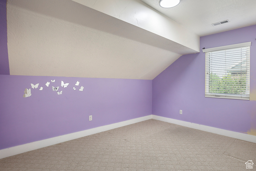 Bonus room featuring lofted ceiling, carpet, and baseboards