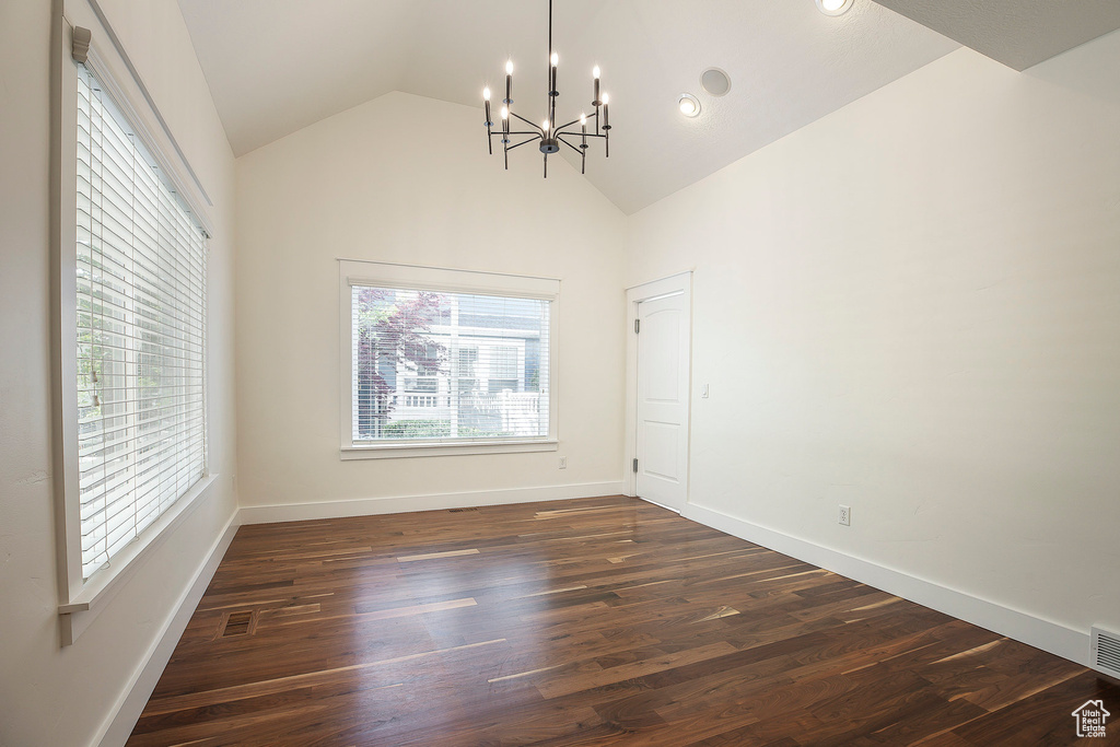 Unfurnished dining area with a chandelier, vaulted ceiling, dark wood finished floors, and baseboards