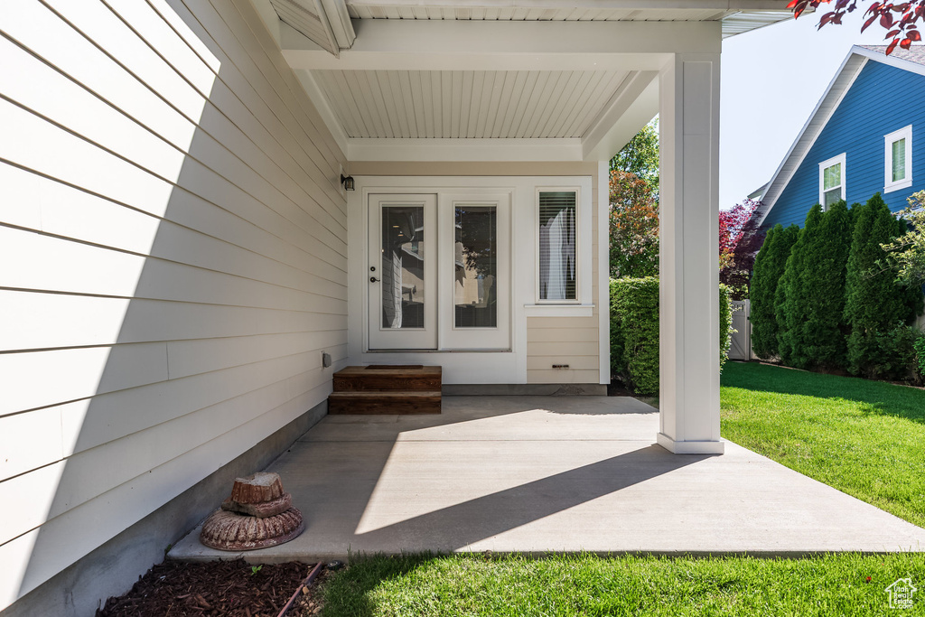 Doorway to property with a patio area and a lawn
