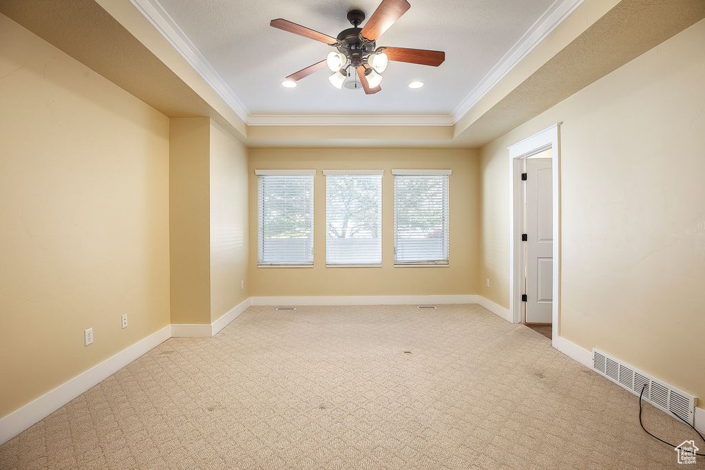 Carpeted empty room featuring crown molding, a ceiling fan, a raised ceiling, baseboards, and recessed lighting