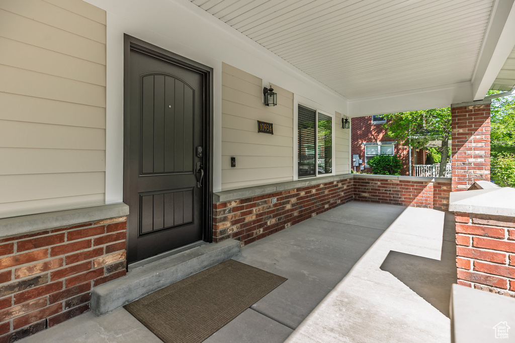 Entrance to property featuring covered porch and brick siding