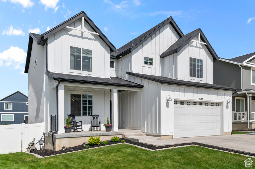 Modern farmhouse with a porch, board and batten siding, an attached garage, and concrete driveway