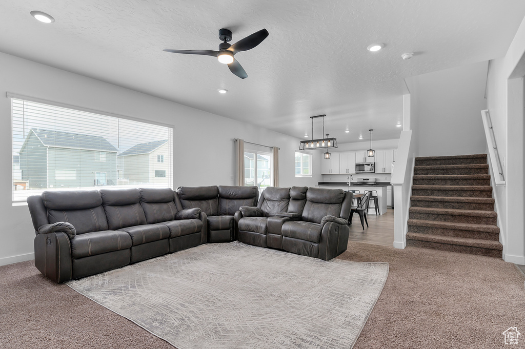 Living room with light colored carpet, ceiling fan, stairway, recessed lighting, and baseboards