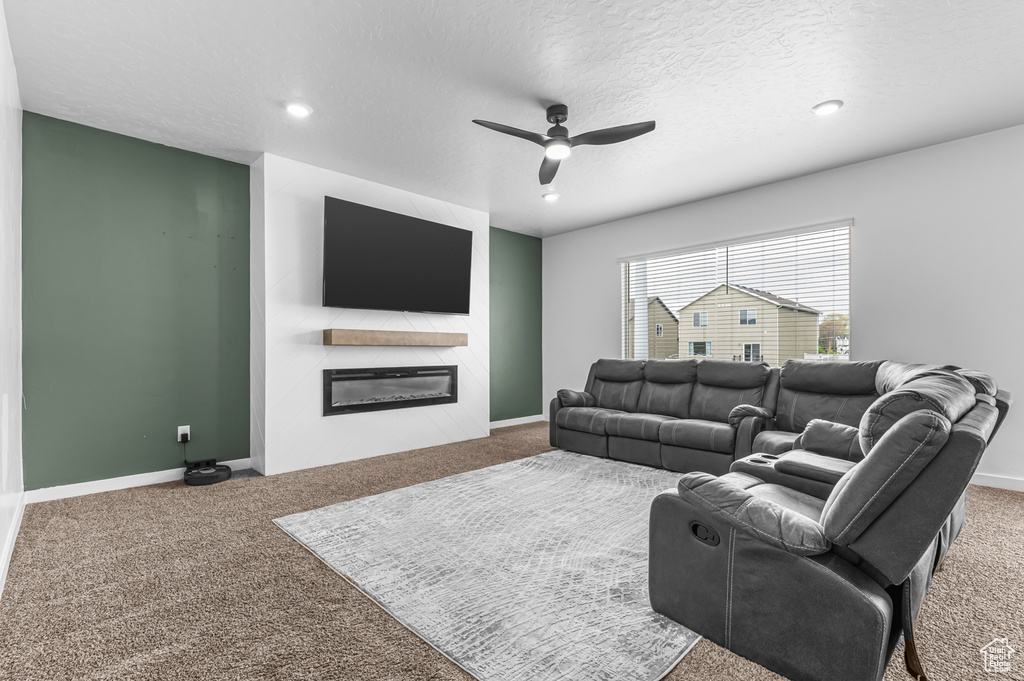 Living area with carpet flooring, a glass covered fireplace, a ceiling fan, recessed lighting, and baseboards