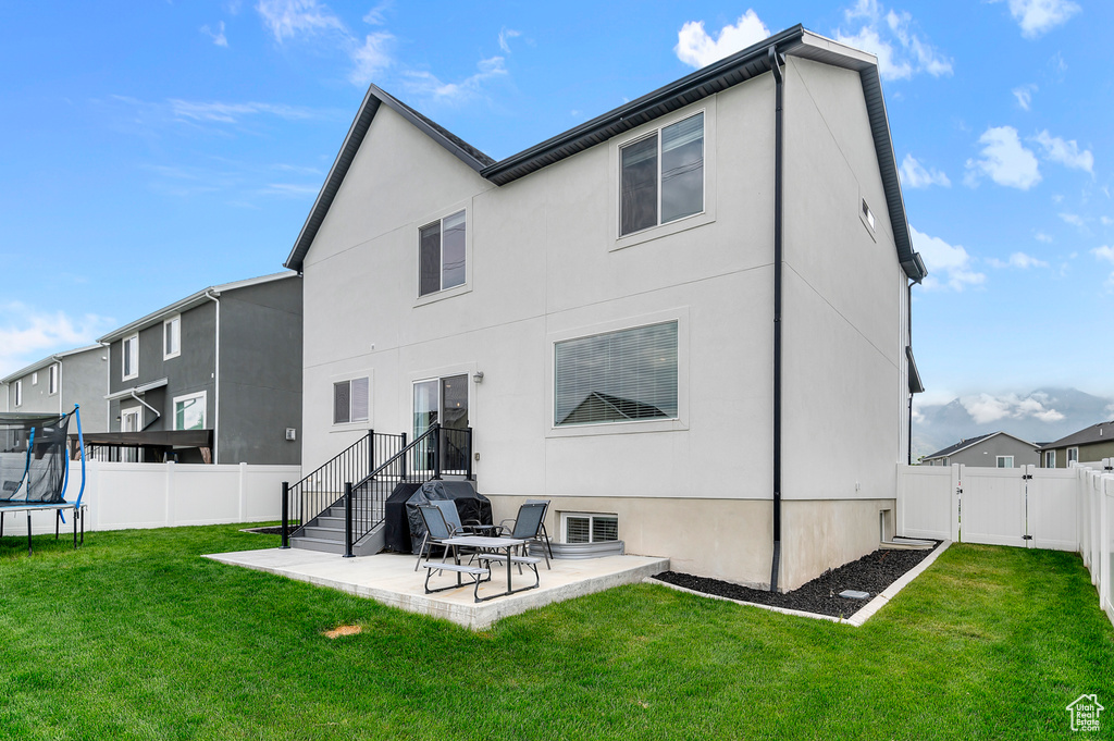 Back of property featuring a trampoline, a patio, a gate, and stucco siding