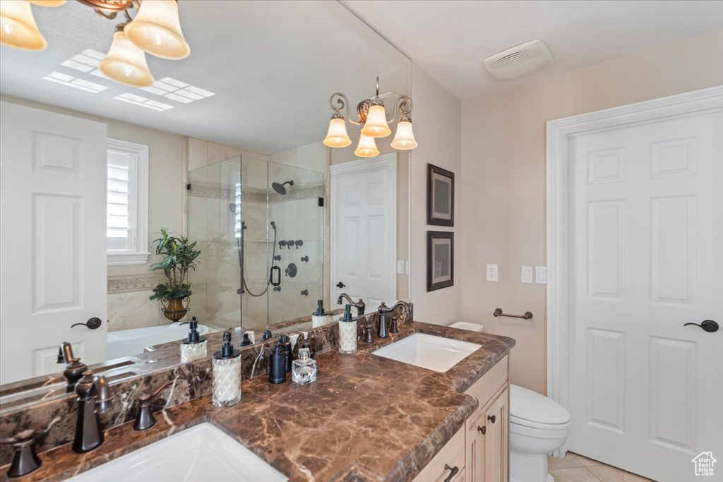 Bathroom with a shower stall, toilet, tile patterned floors, double vanity, and a chandelier