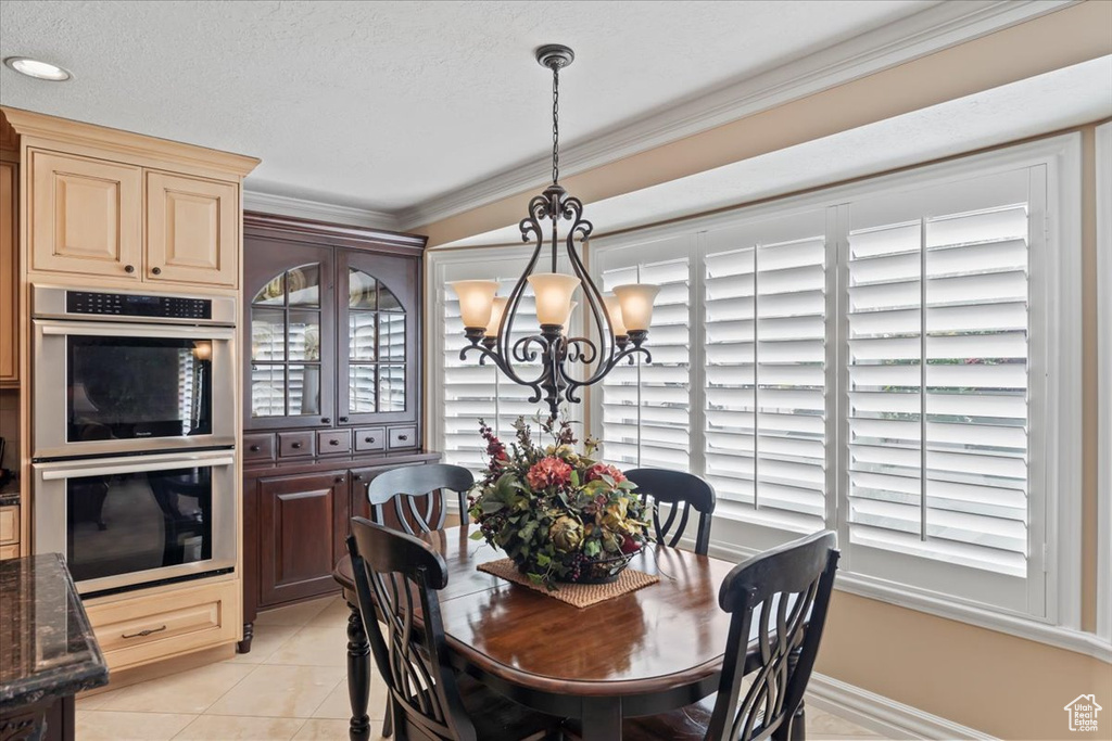 Dining room with a chandelier, crown molding, and light tile patterned floors