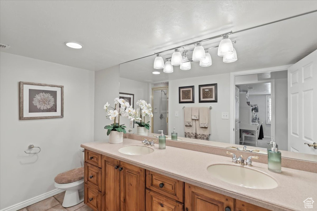 Full bathroom with a stall shower, tile patterned floors, double vanity, toilet, and baseboards